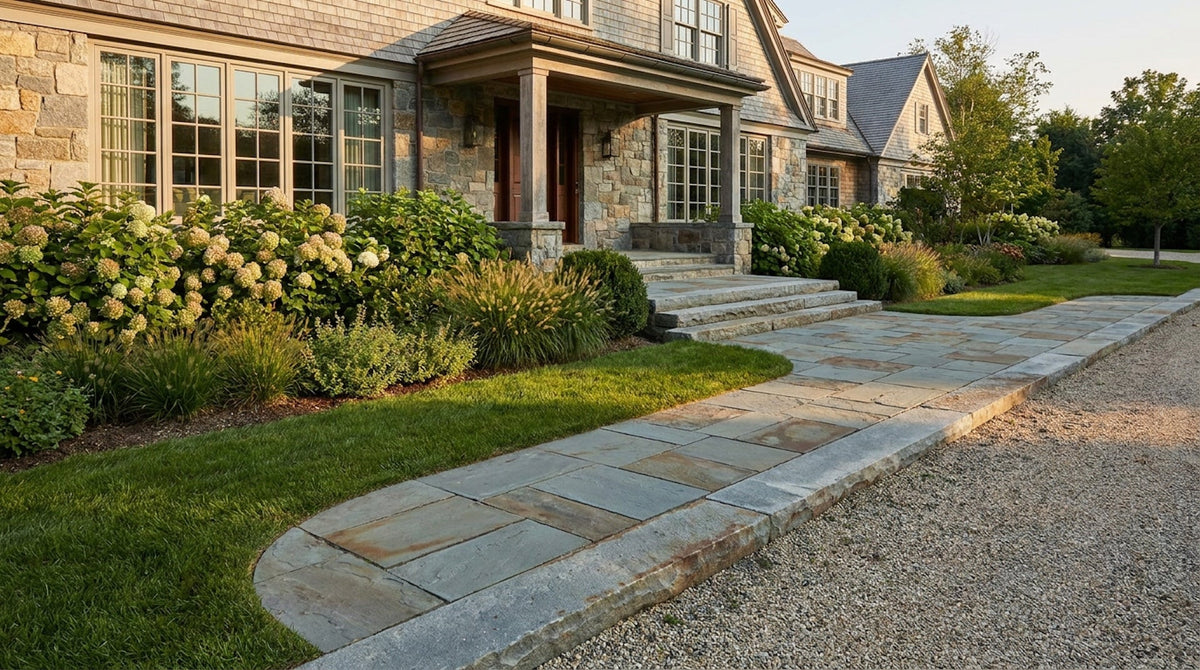 Reclaimed bluestone path and steps beside a gravel drive leading to a shingle house