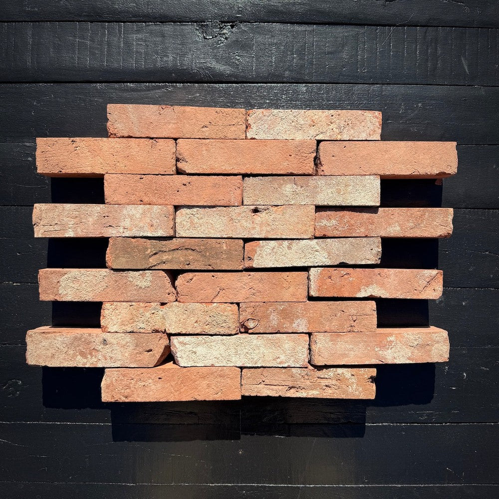 Offset arrangement of natural red clay reclaimed brick veneer in staggered rows